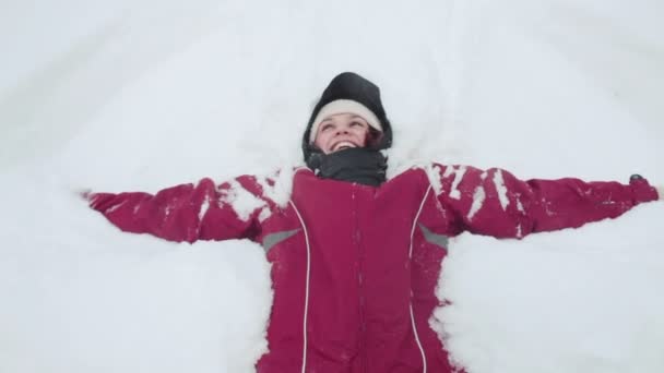 Mujer haciendo ángel de nieve — Vídeos de Stock