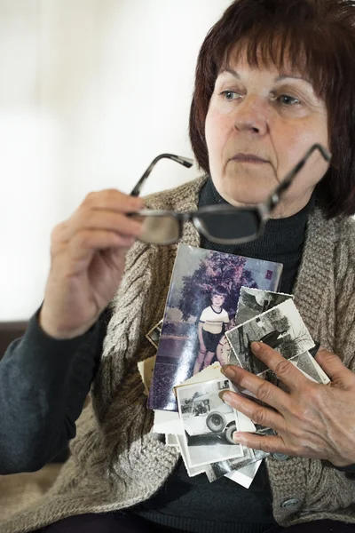 Senior mulher assistindo fotos antigas — Fotografia de Stock