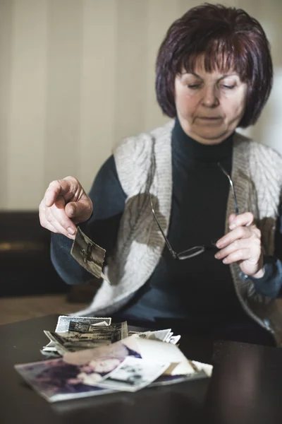 Senior vrouw kijken naar oude foto 's — Stockfoto