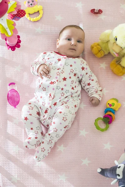 Meisje van de baby in een bed met speelgoed — Stockfoto