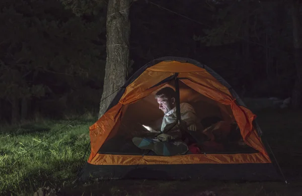 Man watching his smartphone in tent — Stock Photo, Image