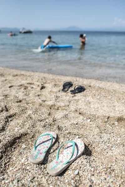 Tofflor i sanden på stranden — Stockfoto