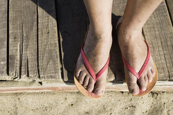 Woman feet on beach in pink thongs — Stock Photo, Image