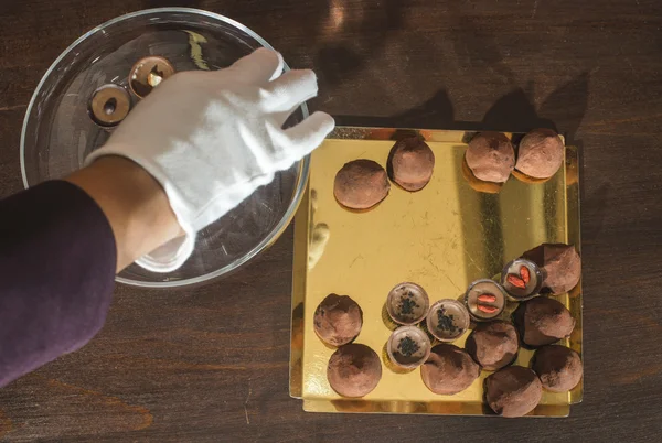 Mano y chocolates en plato — Foto de Stock