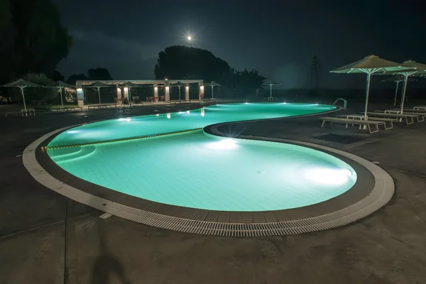 Pool, sunbeds and umbrellas at night — Stock Photo, Image