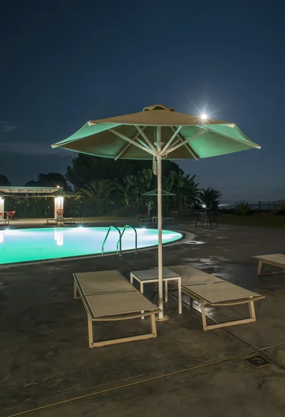 Pool, sunbeds and umbrellas at night — Stock Photo, Image