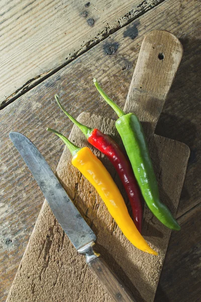 Pimentos quentes na placa de corte de madeira — Fotografia de Stock