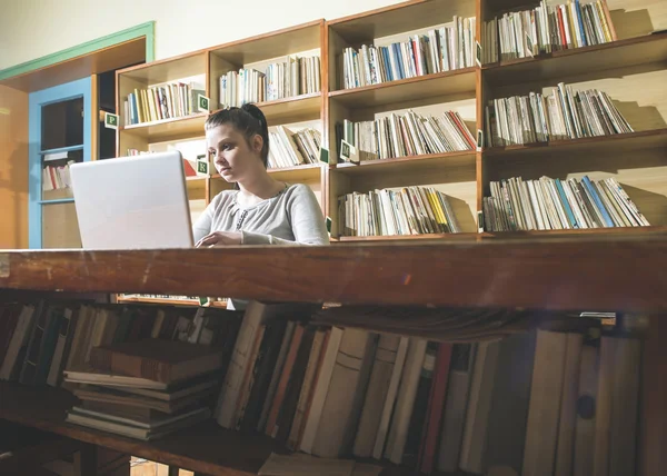 Étudiante et ordinateur portable dans une bibliothèque — Photo