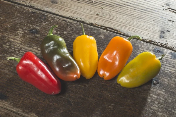 Multicolored peppers on wooden board — Stock Photo, Image