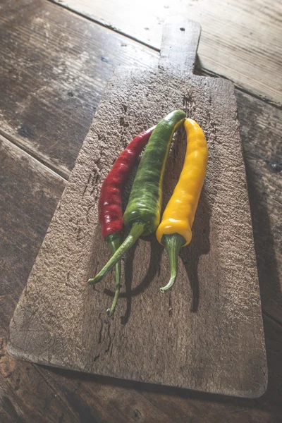 Pimentos quentes na placa de corte de madeira — Fotografia de Stock