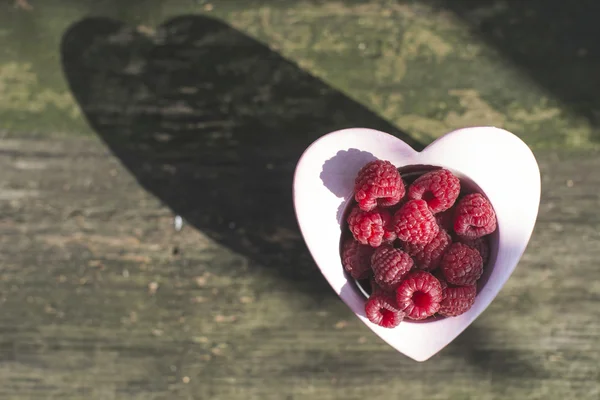 Raspberries in bowl on wood — Stock Photo, Image