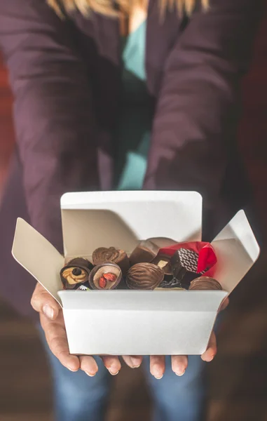 Mãos segurando caixa de chocolates — Fotografia de Stock