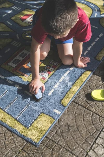 L'enfant nettoie le tapis — Photo