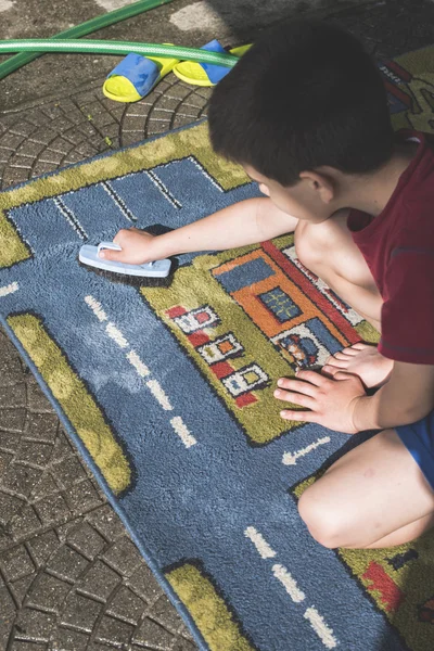Barn är att rengöra mattan — Stockfoto