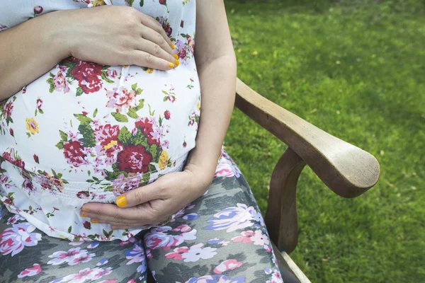 Zwangere vrouw zitten in de tuin — Stockfoto