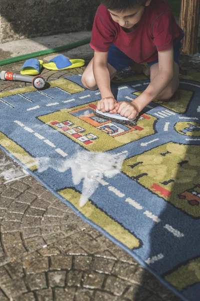 L'enfant nettoie le tapis — Photo