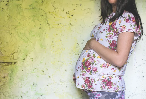 Mujer embarazada delante de la pared amarilla —  Fotos de Stock