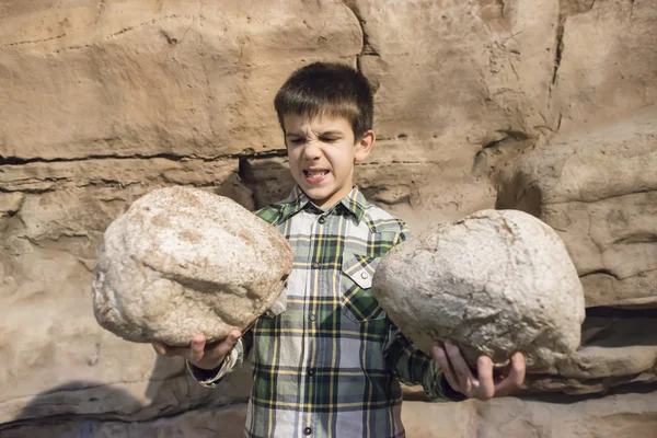 Child holding heavy stones — Stock Photo, Image