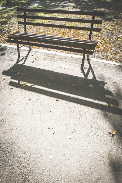 Скамейка в парке и осенние листья — стоковое фото