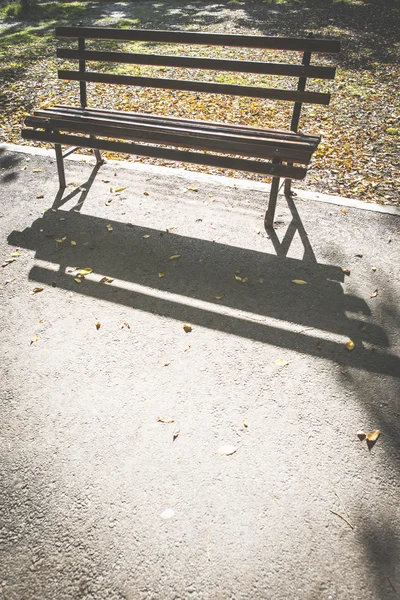 Banco en un parque y hojas de otoño — Foto de Stock