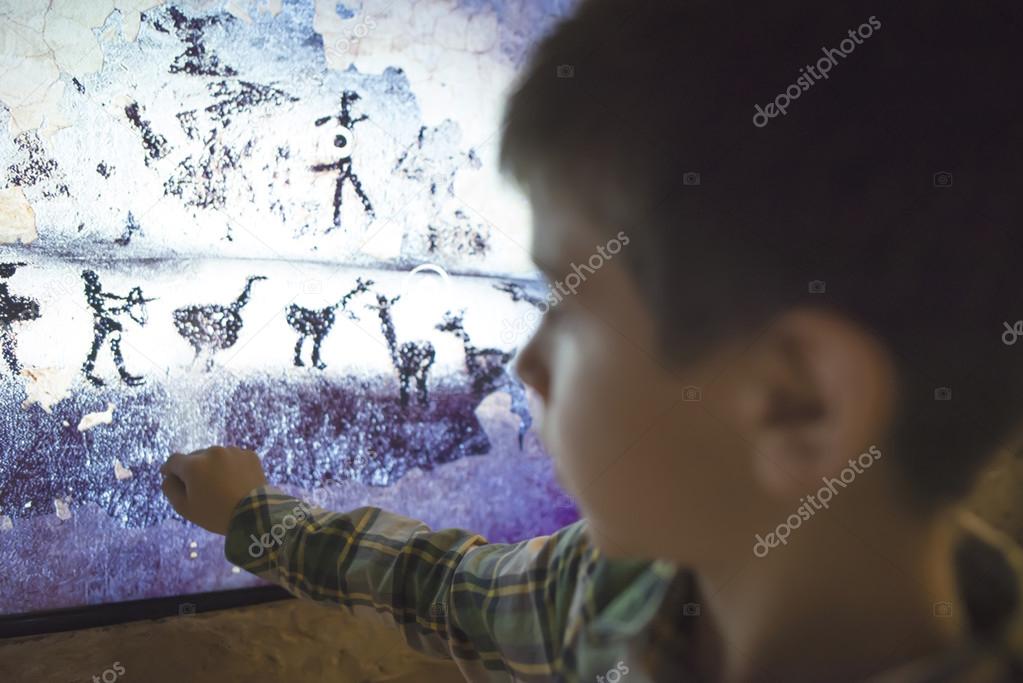 Child looks at ancient mural