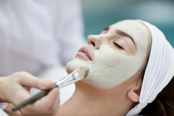 Retrato de una hermosa chica con una toalla en la cabeza aplicando mascarilla facial — Foto de Stock