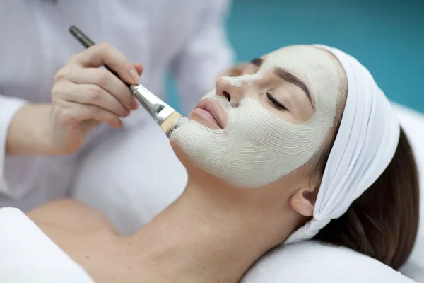 Retrato de una hermosa chica con una toalla en la cabeza aplicando mascarilla facial — Foto de Stock