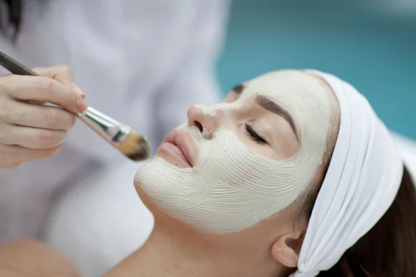 Retrato de una hermosa chica con una toalla en la cabeza aplicando mascarilla facial — Foto de Stock