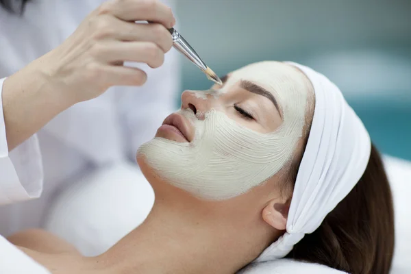 Retrato de una hermosa chica con una toalla en la cabeza aplicando mascarilla facial — Foto de Stock