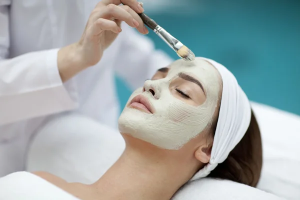 Retrato de una hermosa chica con una toalla en la cabeza aplicando mascarilla facial — Foto de Stock