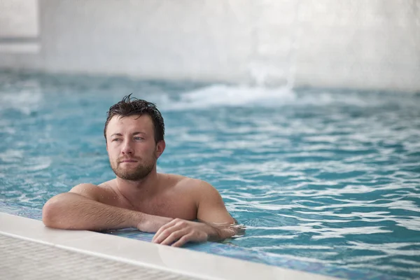 Hombre inclinado en el borde de la piscina — Foto de Stock