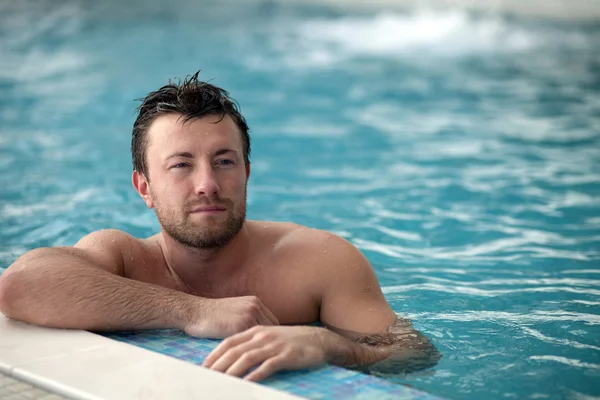 Man leaning at edge of swimming pool — Stock Photo, Image