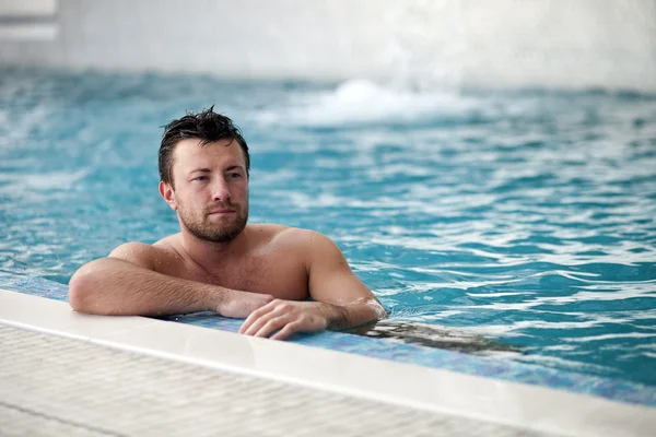 Man leaning at edge of swimming pool — Stock Photo, Image