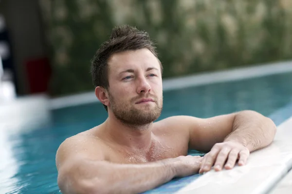 Man leaning at edge of swimming pool — Stock Photo, Image