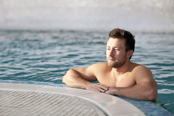 Man leaning at edge of swimming pool — Stock Photo, Image