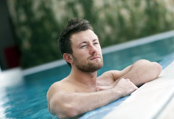 Man leaning at edge of swimming pool — Stock Photo, Image