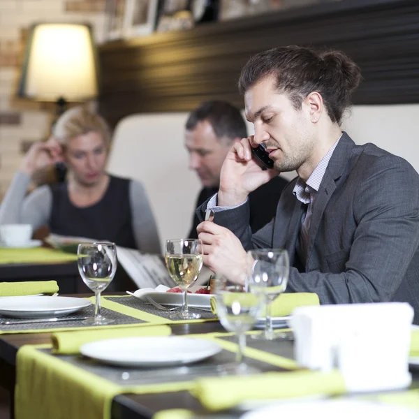 Le jeune homme qui travaille avec l'ordinateur portable utilise le téléphone. Ses collègues mènent la conversation — Photo