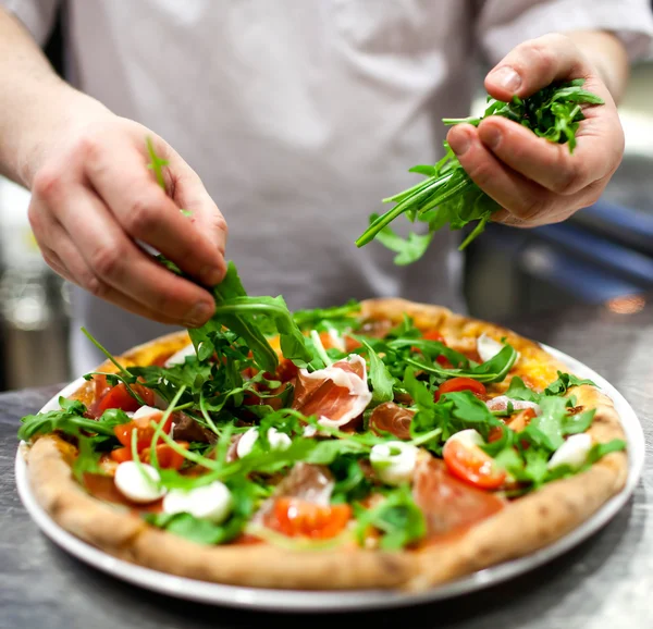 Şef mutfakta pizza yapıyor.