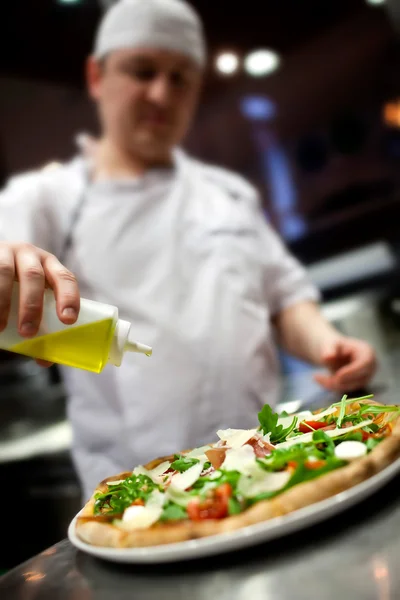 Záběr rukou šéfkuchaře Baker v bílé uniformě pizzu v kuchyni — Stock fotografie