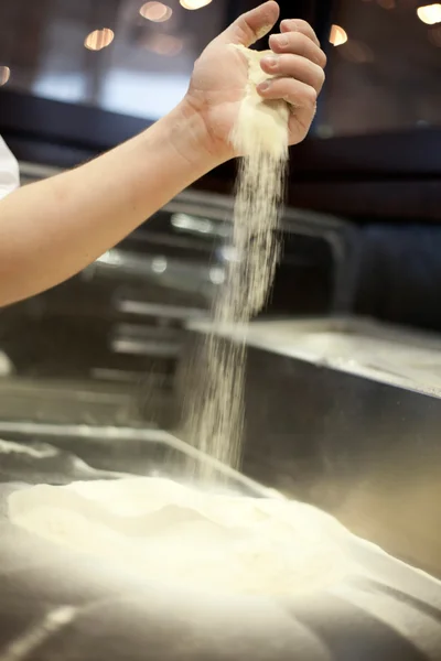 Espolvorear la harina con las manos sobre la masa de pan — Foto de Stock