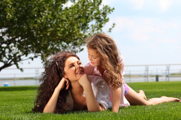 Young mother and daughter laying on the grass — Stock Photo, Image