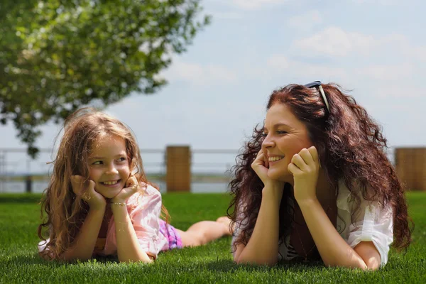 Young mother and daughter laying on the grass — Stock Photo, Image