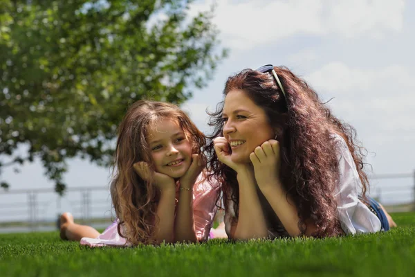 Young mother and daughter laying on the grass — Stock Photo, Image