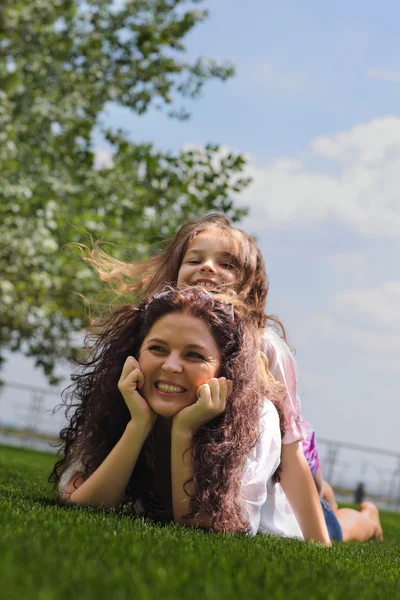 Young mother and daughter laying on the grass — Stock Photo, Image