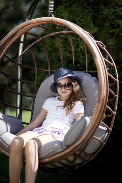 Portret van een jong meisje, zittend in rieten stoel — Stockfoto