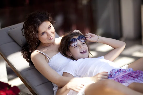 Woman and young girl sitting on patio smiling — Stock Photo, Image