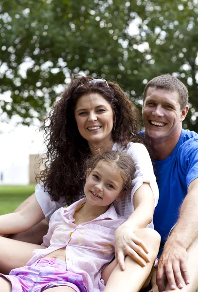 Glücklich schöne junge Familie auf dem grünen Gras liegend. drei fröhliche Menschen — Stockfoto