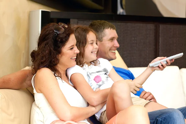Feliz familia joven wathching tv plana en casa moderna interior —  Fotos de Stock