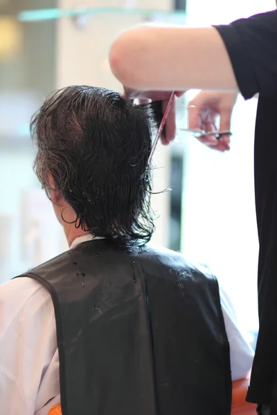 Un hombre corta el pelo en una barbería. Maestro joven estilista. Céntrate en el pelo gris — Foto de Stock