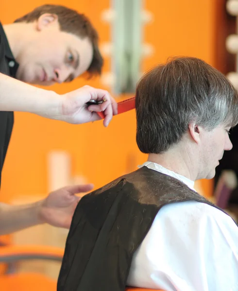 Un hombre corta el pelo en una barbería. Maestro joven estilista. Céntrate en el pelo gris — Foto de Stock